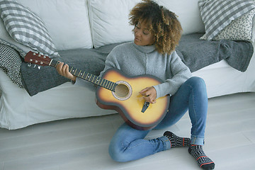 Image showing Young woman playing guitar at home