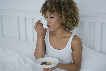 Image showing Young woman eating breakfast in bed
