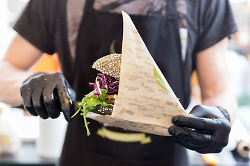 Image showing Chef serving organic vegetarian fish burger at international urban street food festival.