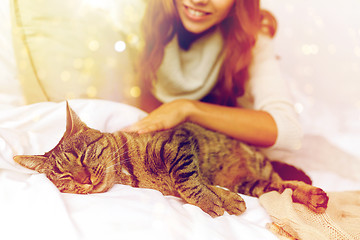 Image showing happy young woman with cat lying in bed at home