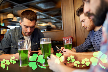 Image showing friends with smarphones and green beer at pub