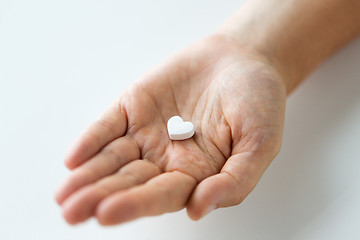 Image showing close up of hand holding medicine heart pill