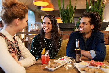 Image showing happy friends with drinks and food at bar or cafe