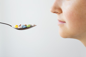 Image showing close up of female face and spoon with pills