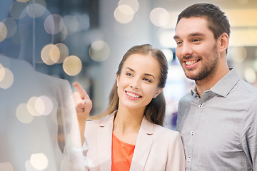 Image showing happy couple pointing finger to shop window