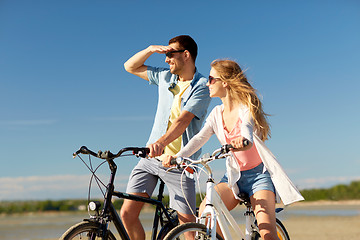 Image showing happy young couple riding bicycles at seaside