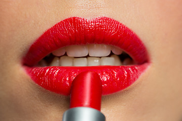 Image showing close up of woman applying red lipstick to lips