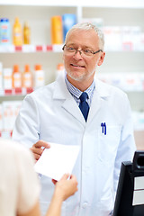 Image showing senior apothecary with prescription at pharmacy