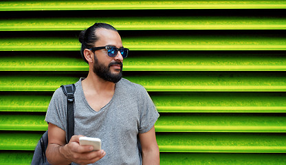 Image showing man in sunglasses with smartphone and bag at wall