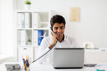 Image showing happy businessman calling on desk phone at office