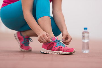 Image showing Young woman tying shoelaces on sneakers