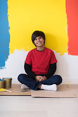 Image showing young boy painter resting after painting the wall