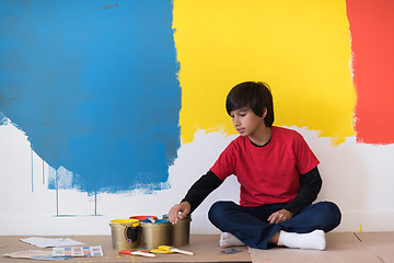 Image showing young boy painter resting after painting the wall