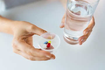 Image showing close up of hands with pills and glass of water