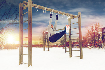 Image showing young man exercising on horizontal bar in winter