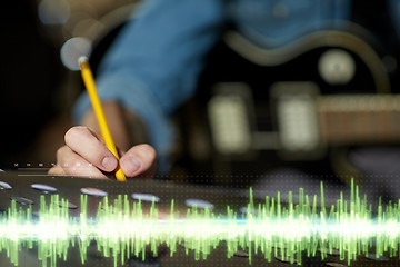 Image showing man with guitar writing to music book at studio