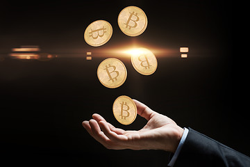 Image showing close up of businessman hand with bitcoins