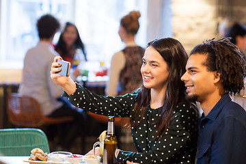 Image showing happy couple taking selfie at restaurant or bar