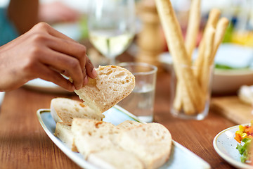 Image showing hand taking piece of bread from plate