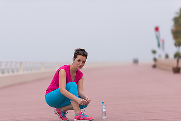 Image showing Young woman tying shoelaces on sneakers