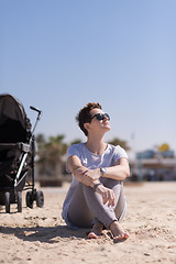 Image showing Young mother with sunglasses relaxing on beach