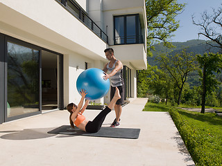 Image showing woman and personal trainer doing exercise with pilates ball