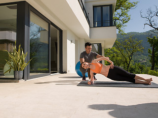 Image showing woman with personal trainer doing morning yoga exercises