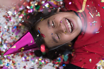 Image showing kid blowing confetti while lying on the floor