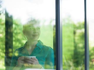 Image showing young woman drinking morning coffee by the window