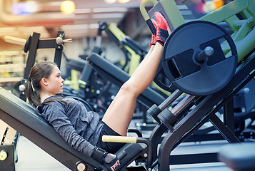 Image showing woman flexing muscles on leg press machine in gym