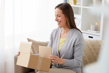 Image showing smiling woman opening parcel box at home