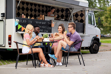 Image showing happy friends with drinks eating at food truck