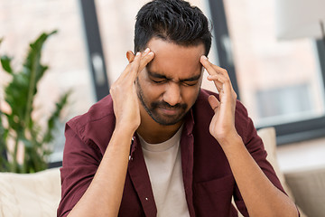 Image showing unhappy man suffering from head ache at home