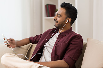 Image showing man in earphones listening to music on smartphone