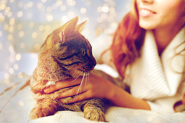 Image showing happy young woman with cat lying in bed at home