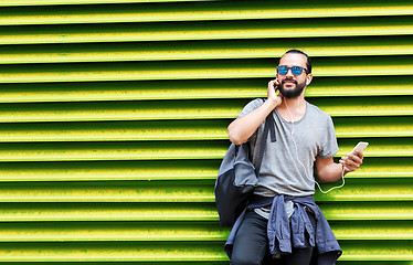 Image showing man with earphones and smartphone over wall