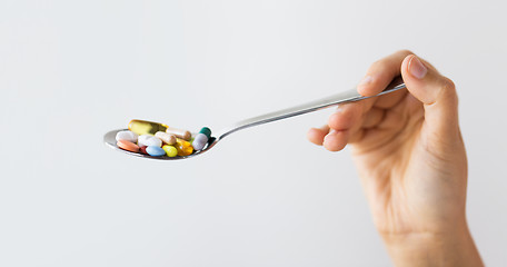 Image showing close up of female hand holding spoon with pills