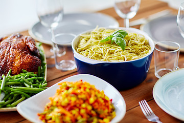 Image showing pasta with basil in bowl and other food on table