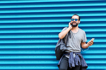 Image showing man with earphones and smartphone over wall