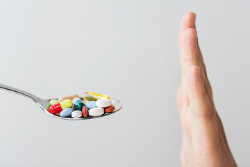 Image showing close up of female hand holding spoon with pills