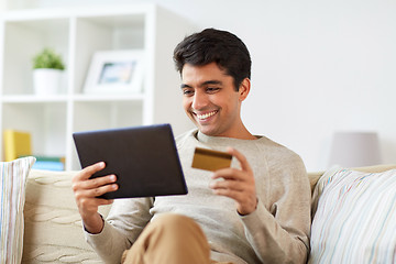 Image showing smiling man with tablet pc and credit card at home