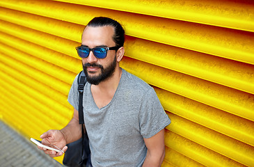 Image showing man in sunglasses with smartphone and bag at wall