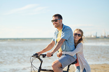 Image showing happy young couple riding bicycle on beach