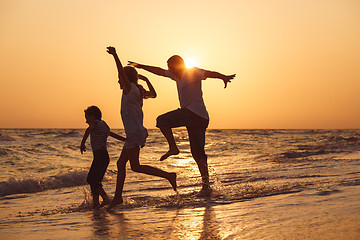 Image showing Father son and daughter playing on the beach at the sunset time.