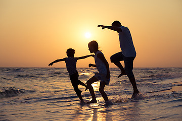 Image showing Father son and daughter playing on the beach at the sunset time.