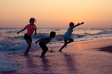 Image showing Happy children playing on the beach at the sunset time.