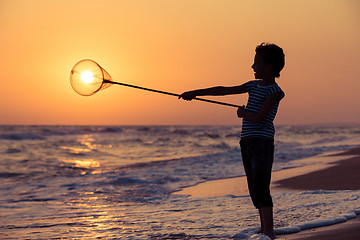 Image showing One happy little boy playing on the beach at the sunset time.