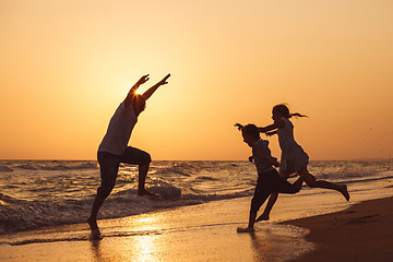 Image showing Father son and daughter playing on the beach at the sunset time.