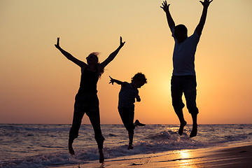 Image showing Father mother and  son  playing on the beach at the sunset time.