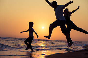 Image showing Father mother and  son  playing on the beach at the sunset time.